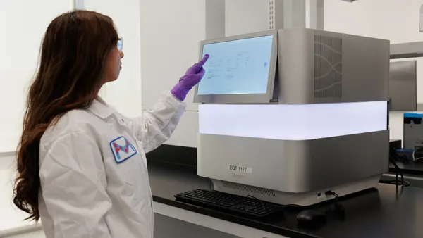 Female working in a lab operating a machine.