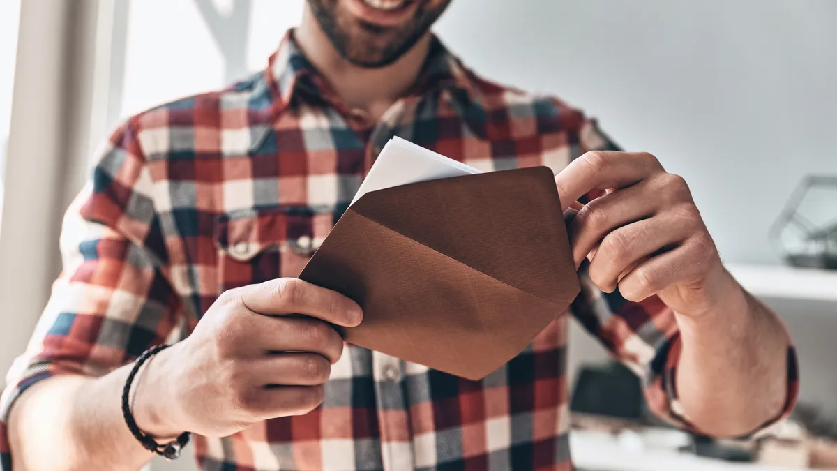 A young man opens an envelope