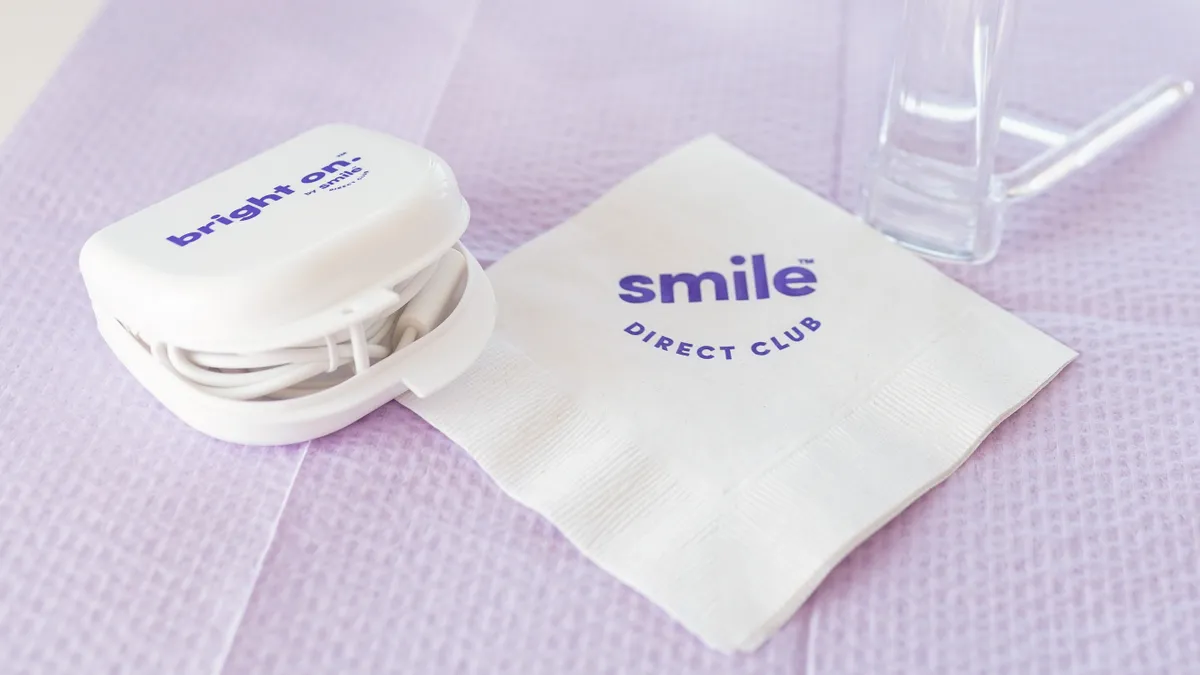 SmileDirectClub branded napkin, retainer holder and mirror on a table