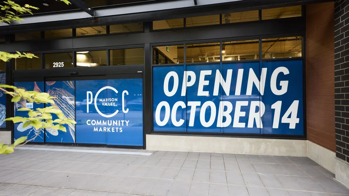 Signs over grocery store window indicating it will open on Oct. 14