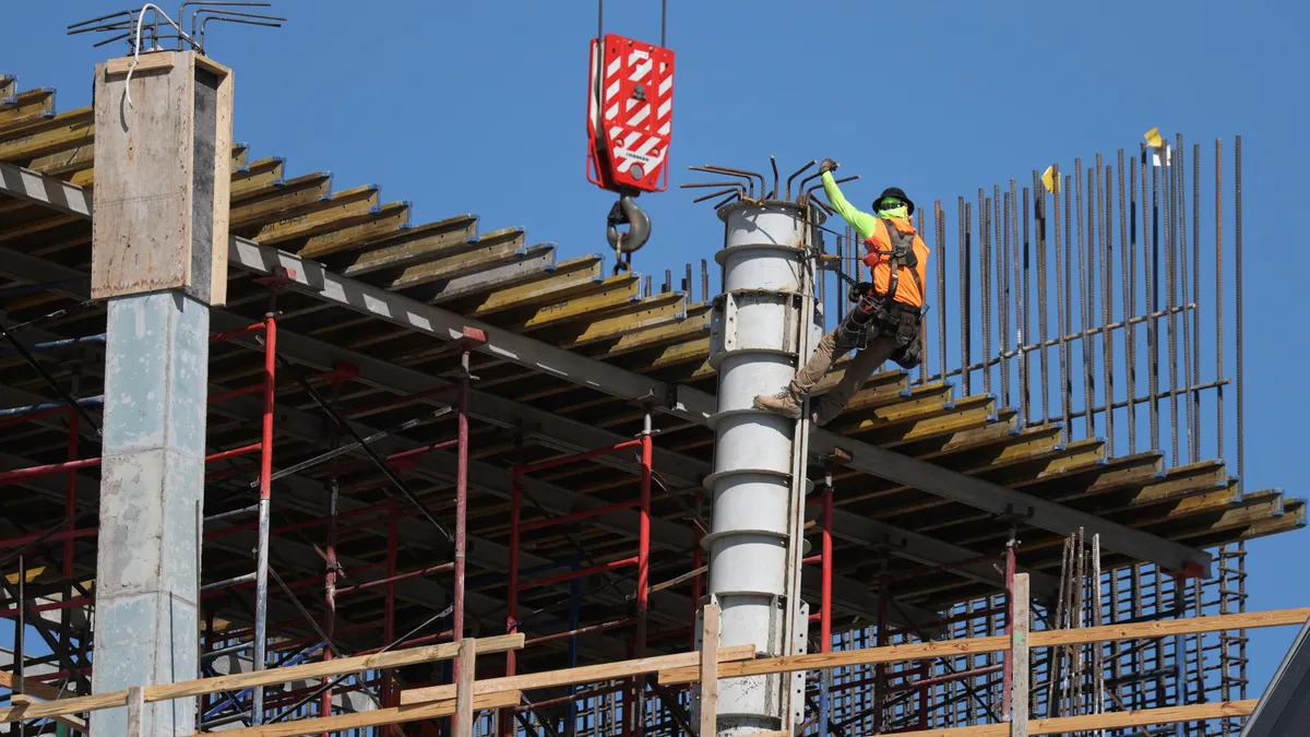 A construction worker climbing a support structure for a building.