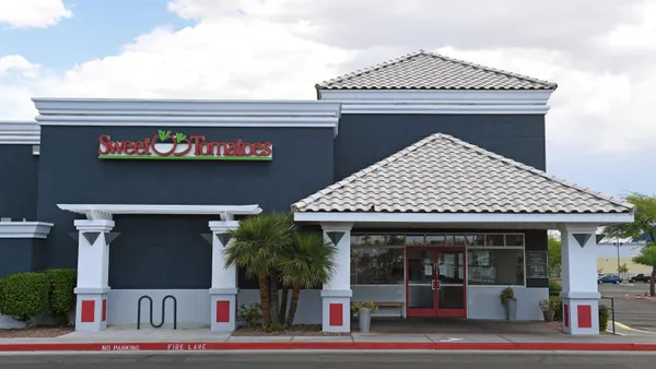 An image of a blue gray buidling with white columns. It has signage that says Sweet Tomatoes in red.