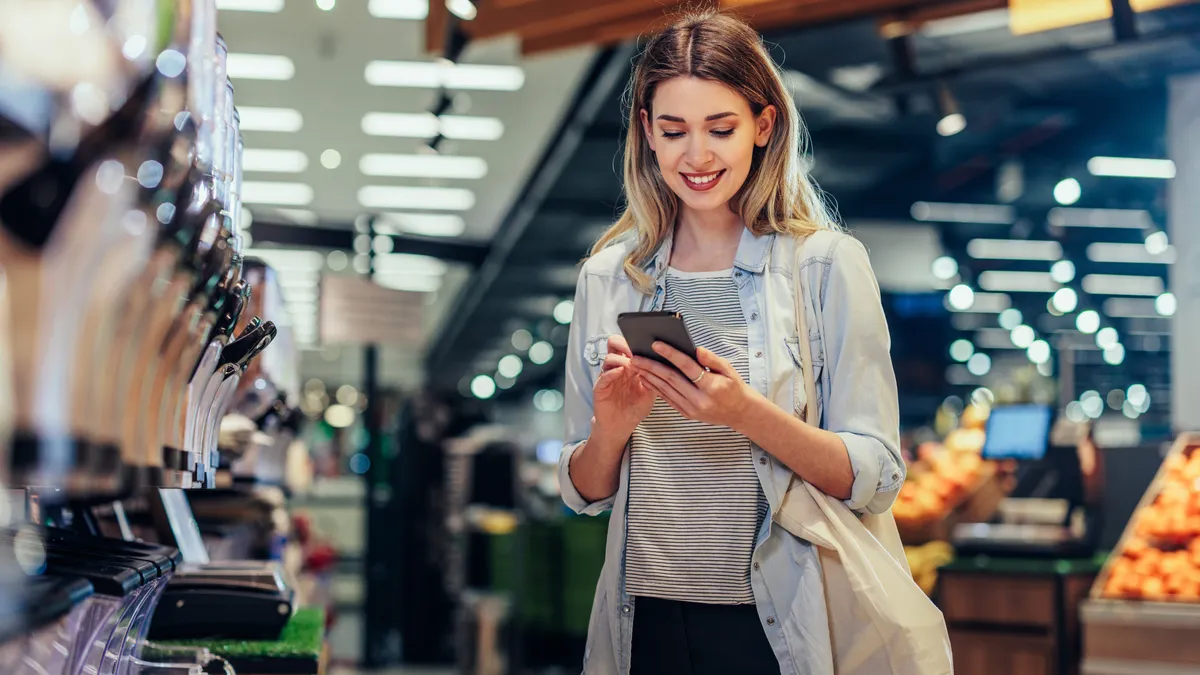 Young women standing with a shopping bag and phone in her hand.