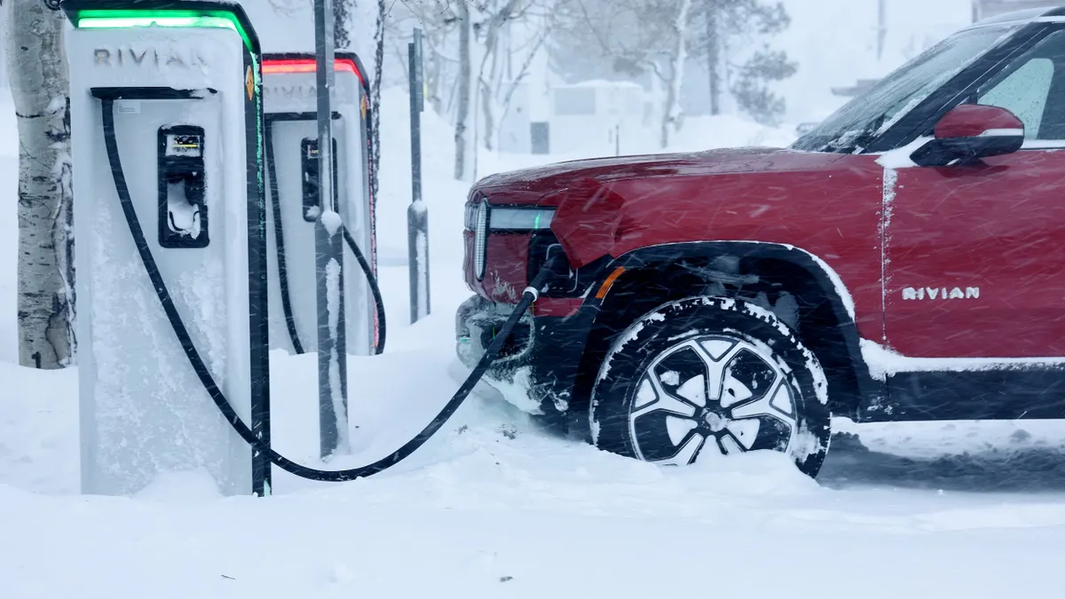 An electric truck charges as a charging station in a snowstorm.