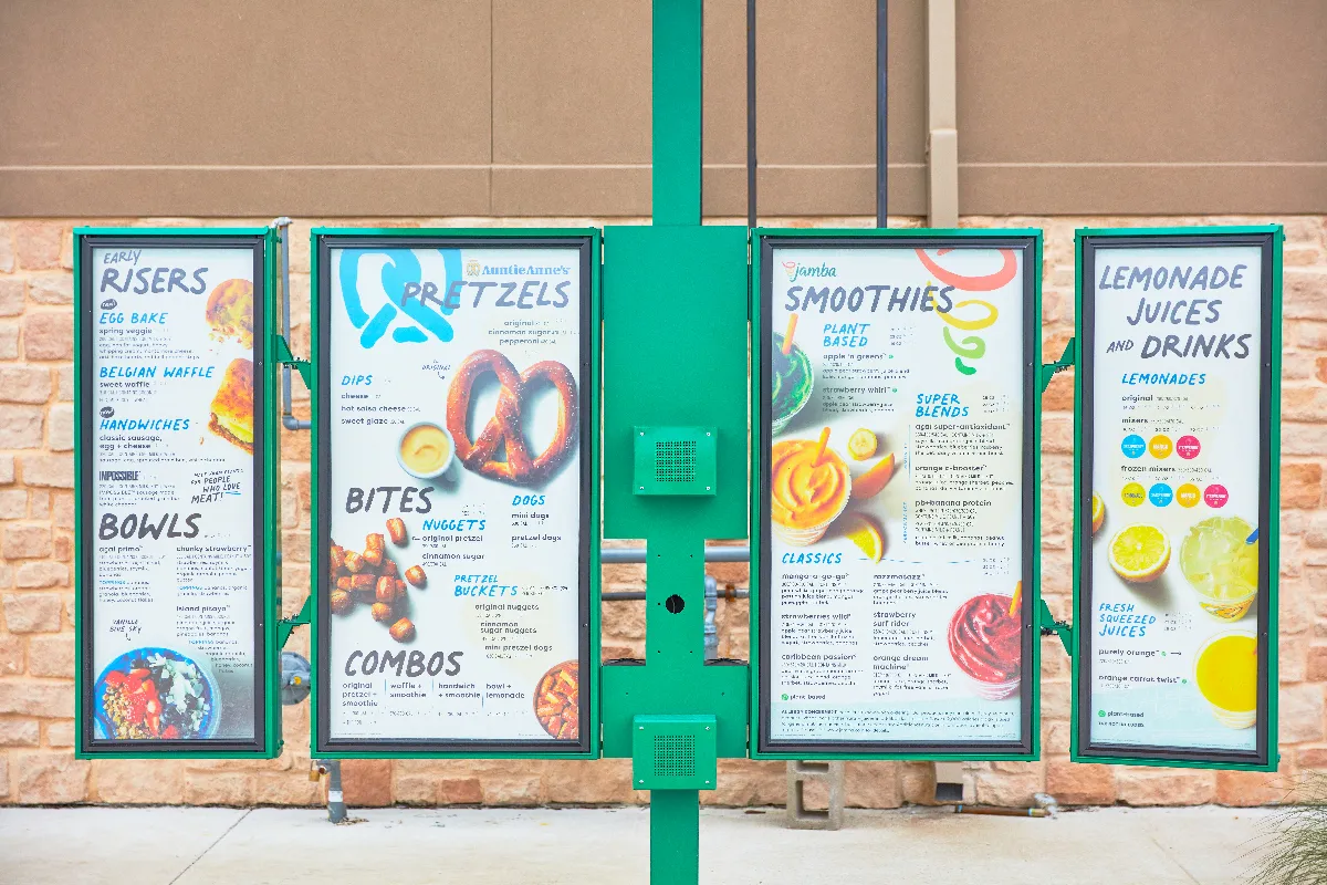 A picture of a green menu board that has multiple food items like pretzels, smoothies and breakfast items.