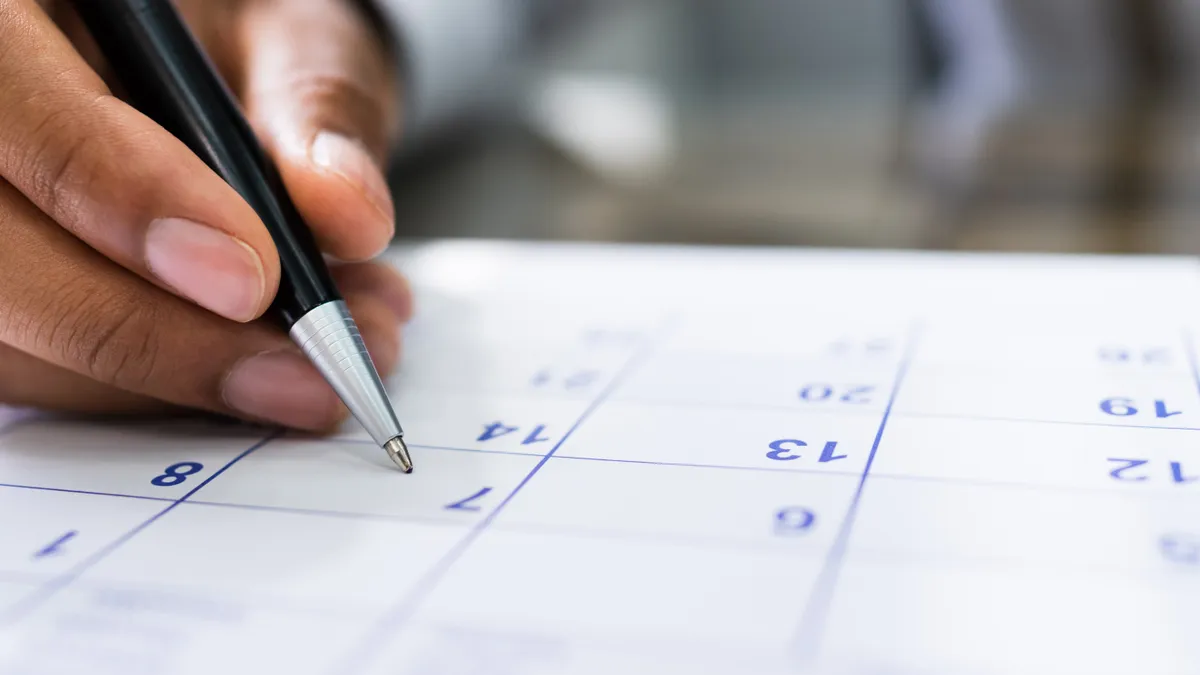 Hand holding a pen writing in a calendar