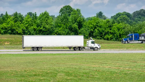 Two heavy trucks meet on an interstate during a summer morning.