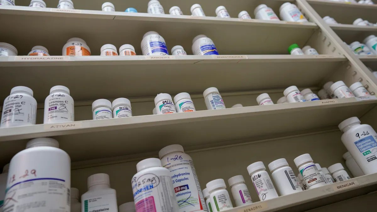 Bottles of medications sit on shelves at a pharmacy.