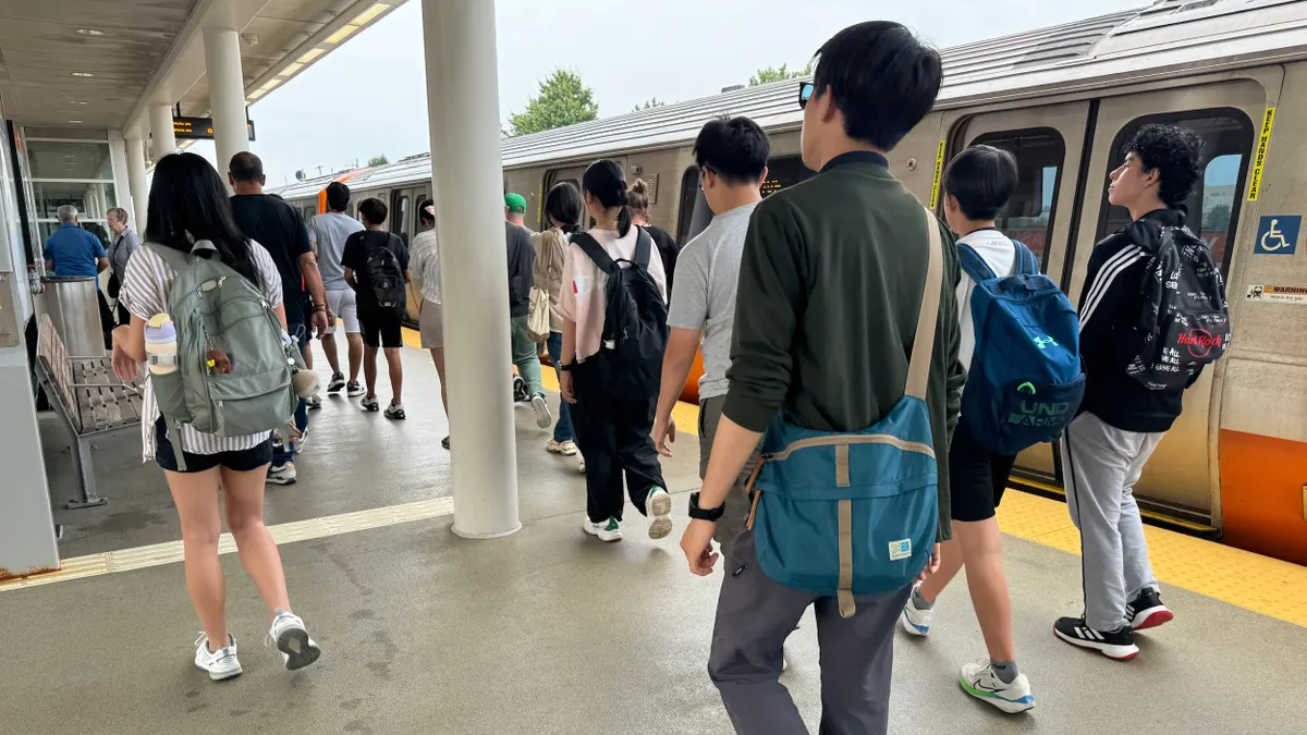People on a station platform walking alongside a train.