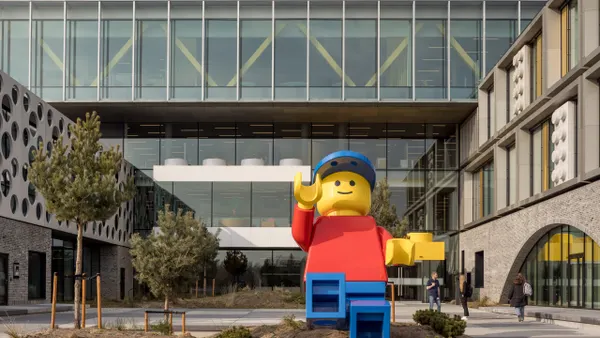 A giant lego figure sculpture sits outside of a Lego campus in Billund.