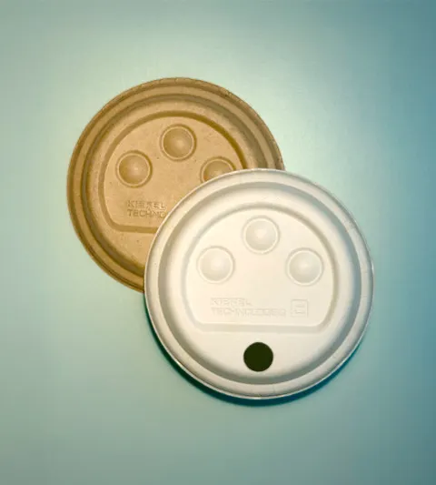 Two beige-colored beverage cup lids on a green background.