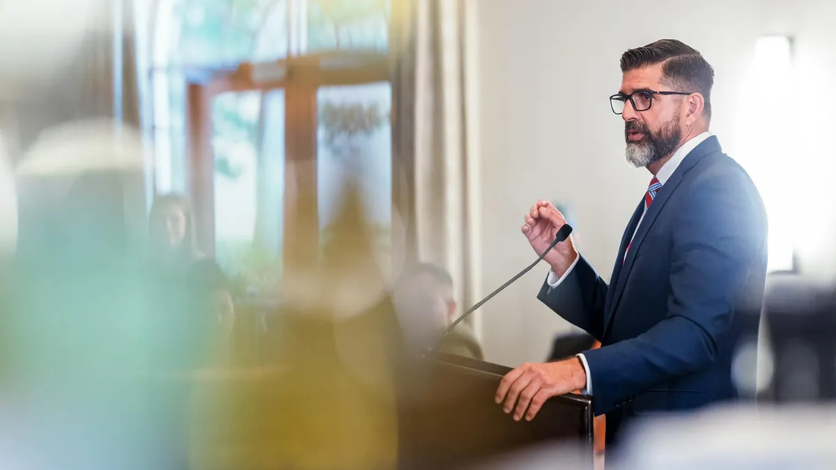 Florida Commissioner of Education Manny Diaz Jr. speaks at a podium with a raised hand