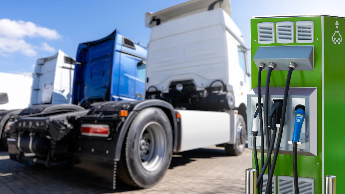 An electric vehicle charging station with a row of tracks in the background.