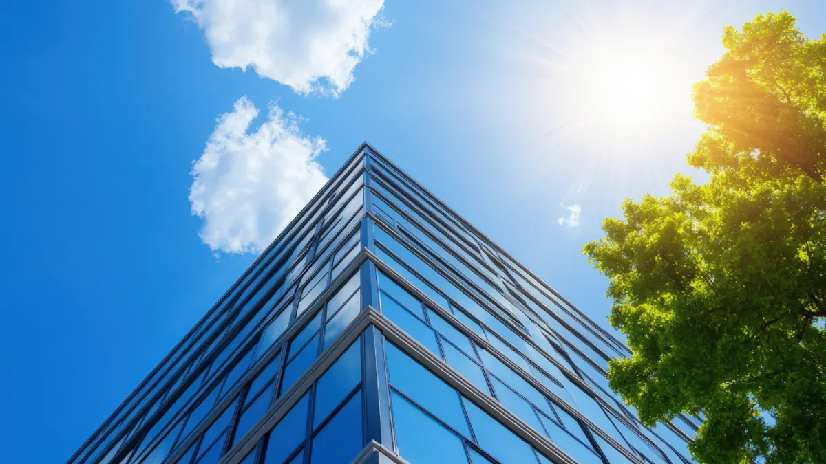 Structural glass wall reflecting blue sky. Abstract modern architecture fragment.