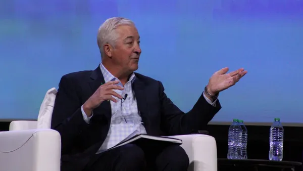 A person sits in a chair and gestures while speaking.