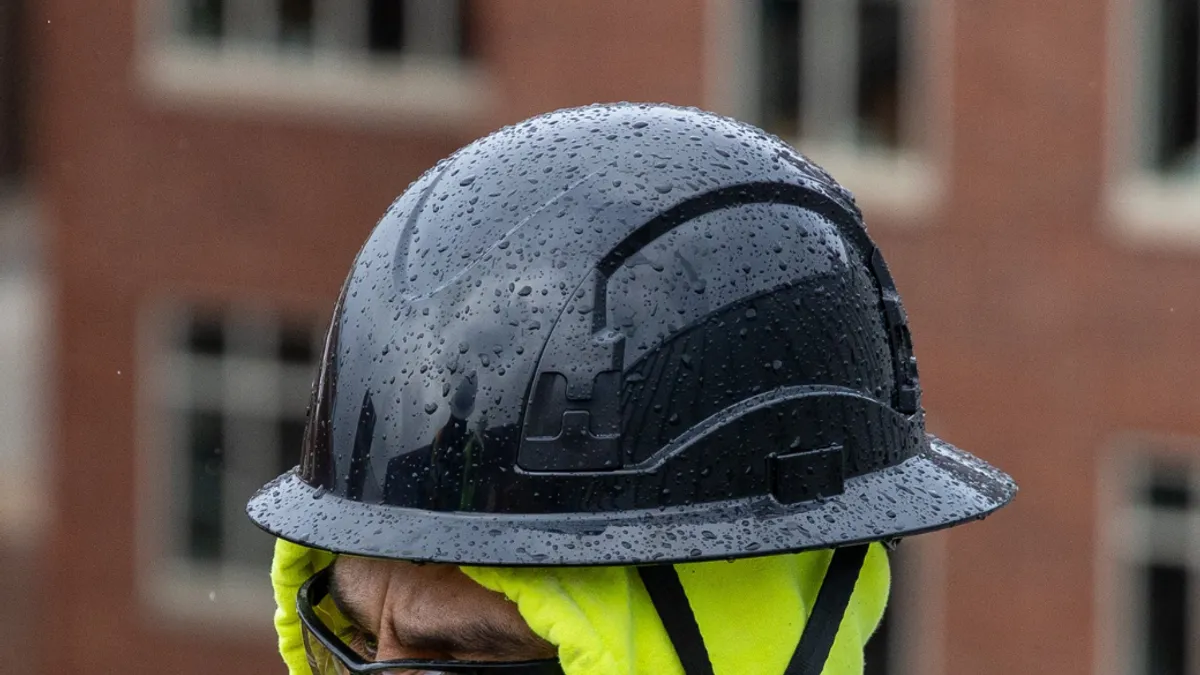 Close up of male site worker wearing black protective head gear.