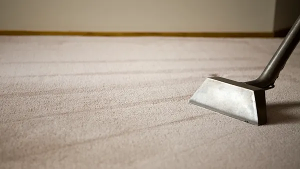 A silver valcuum on a clean, beige carpet.