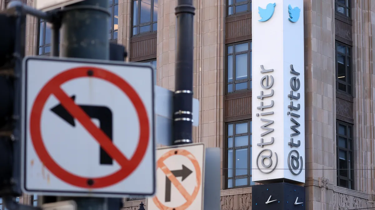 A brown building with white vertical sign with the Twitter logo