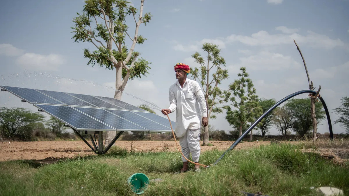 Indian farmer Hari Ram, 62, cleans solar panels on his land, used to power a water pump and irrigation system for crops, on March 25, 2023 in Solawata, India.