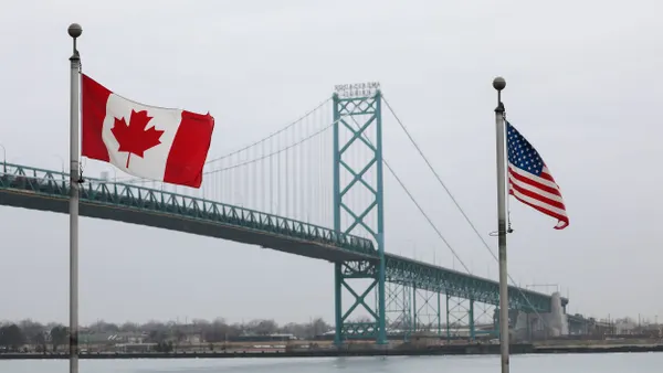 The US and Canada flags wave in front of a bridge
