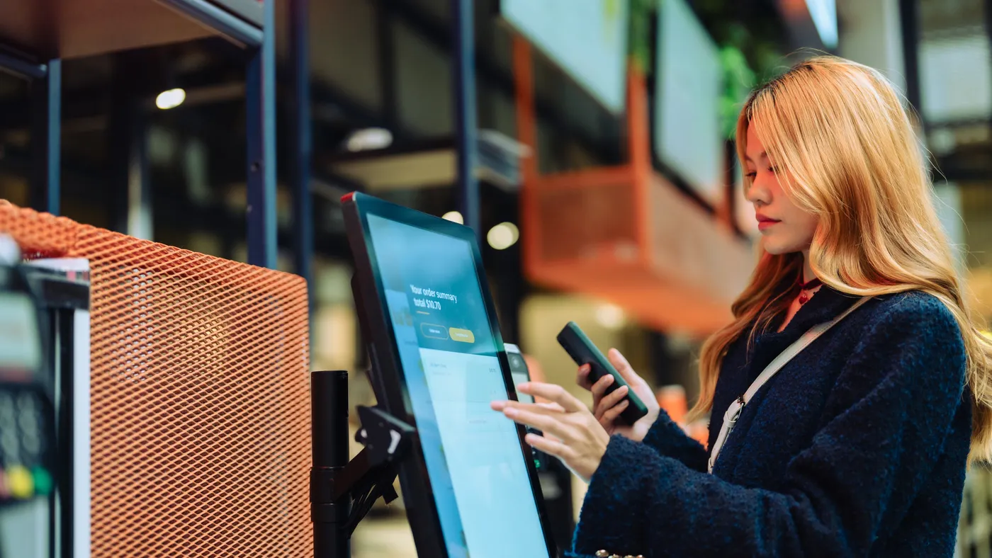 Women pays using automatic payment machine and smartphone.