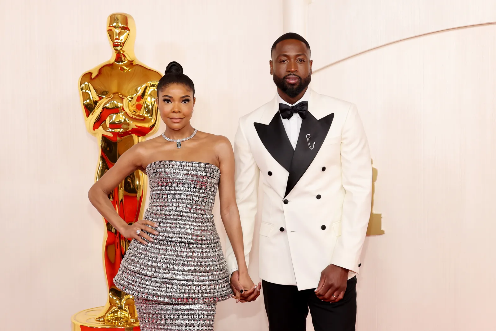 Gabrielle Union-Wade in silver outfit and Dwyane Wade in a black-and-white tuxedo jacket.