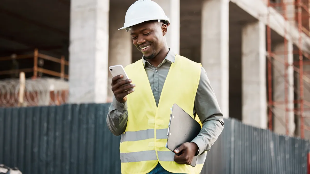 Shot of a young businessman using his smartphone while on a construction site