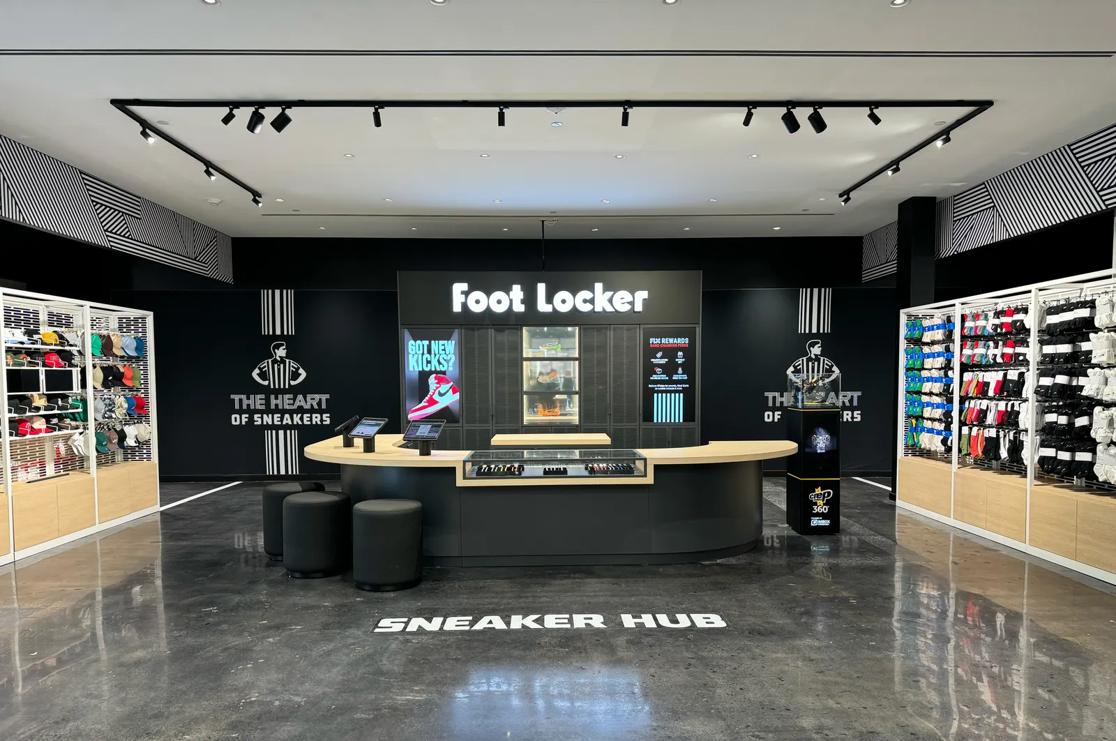 A wall that reads &quot;Foot Locker&quot; with a wood bar-like setup in front of it.