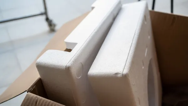 An open corrugated box contains expanded polystyrene foam packaging.