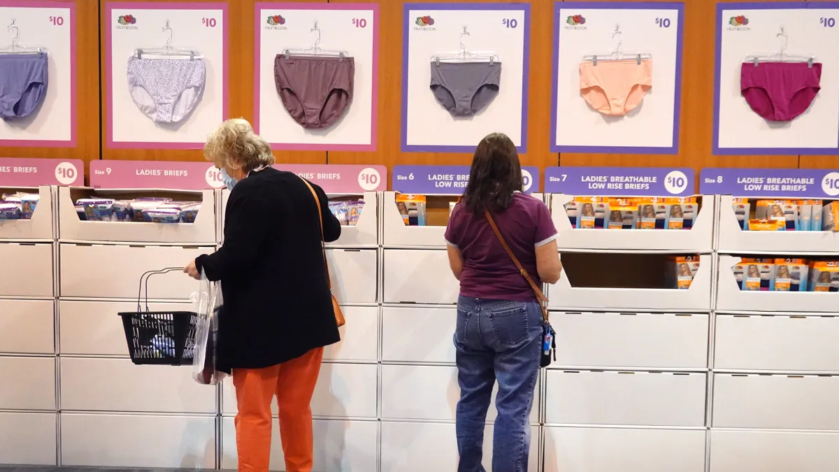 People stand in front of a Fruit of the Loom shopping display.