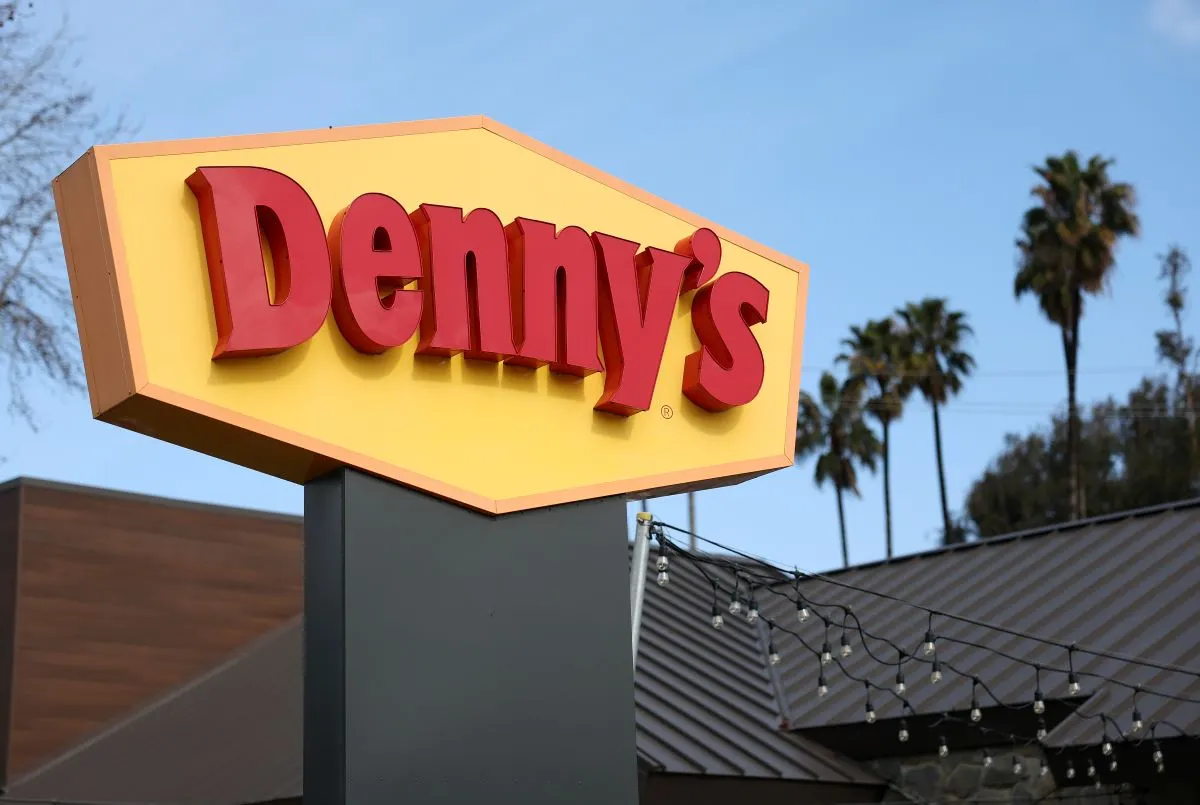 A photograph of a yellow sign with Denny's in red.