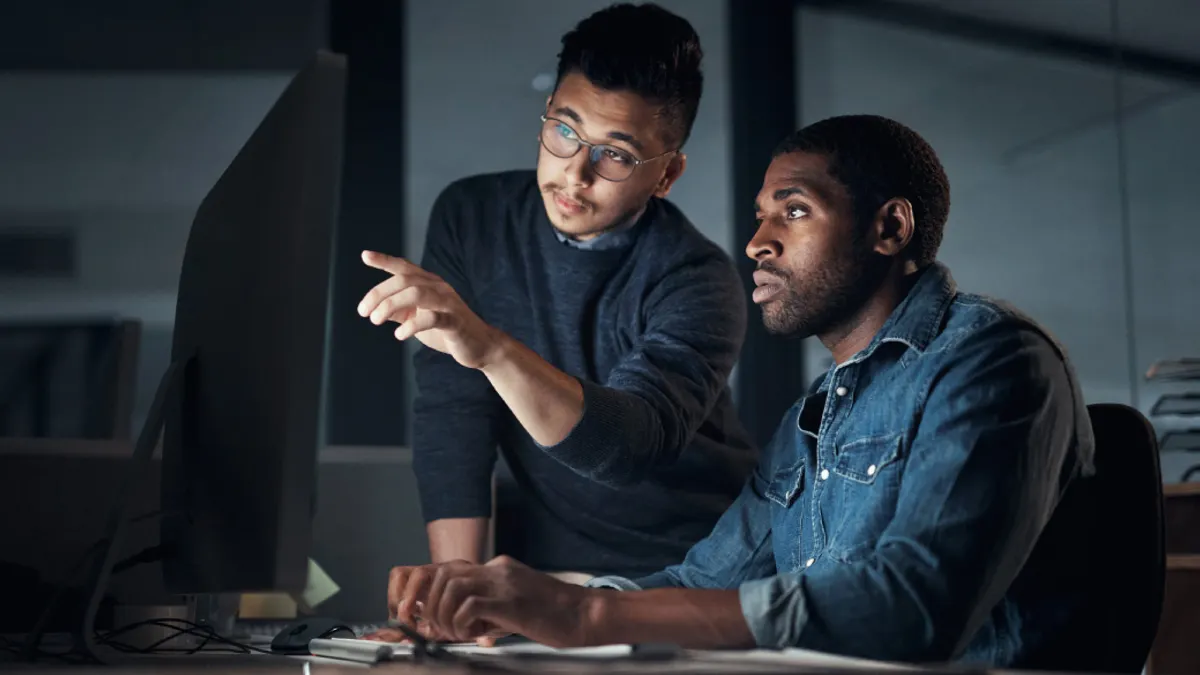 Shot of two young businessmen using a computer during a late night in a modern office