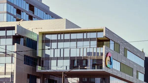 A modern glass and steel building with horizontal lines and a large Google Cloud logo on the corner, featuring reflective windows and power lines crossing in front.