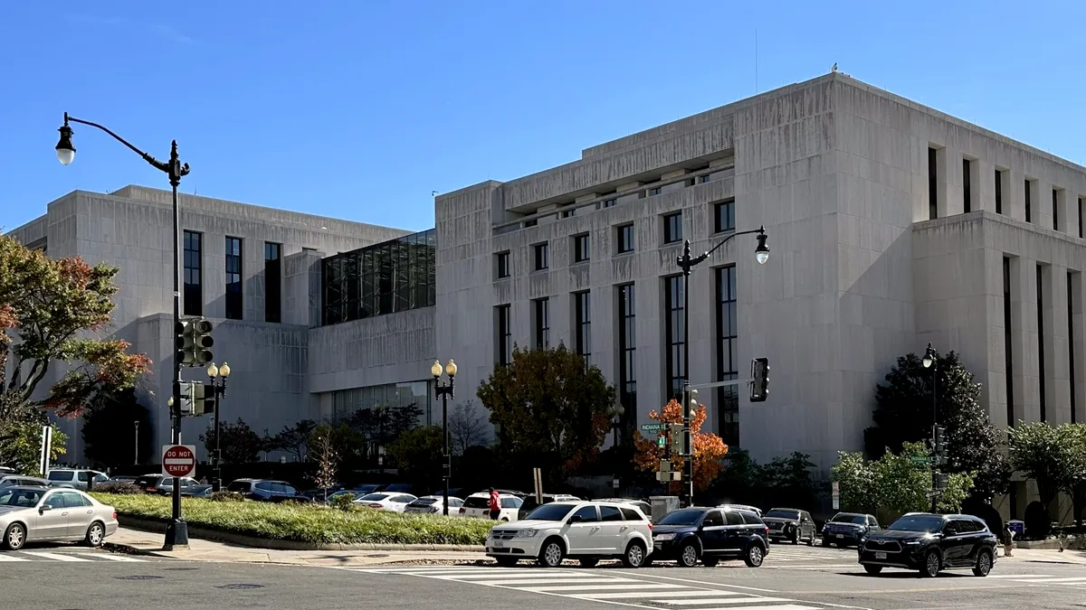 A broad, angular building with cars parked outside