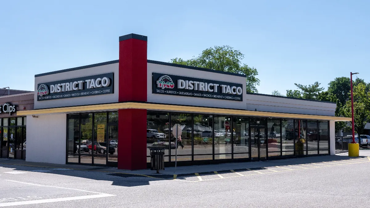 A building with a white exterior and branding for District Taco