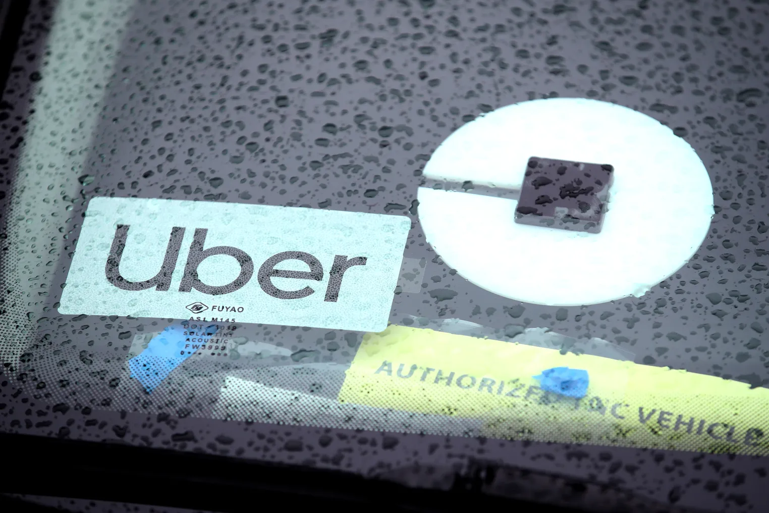 Closeup of an Uber sign on the rear window of a car in the rain.