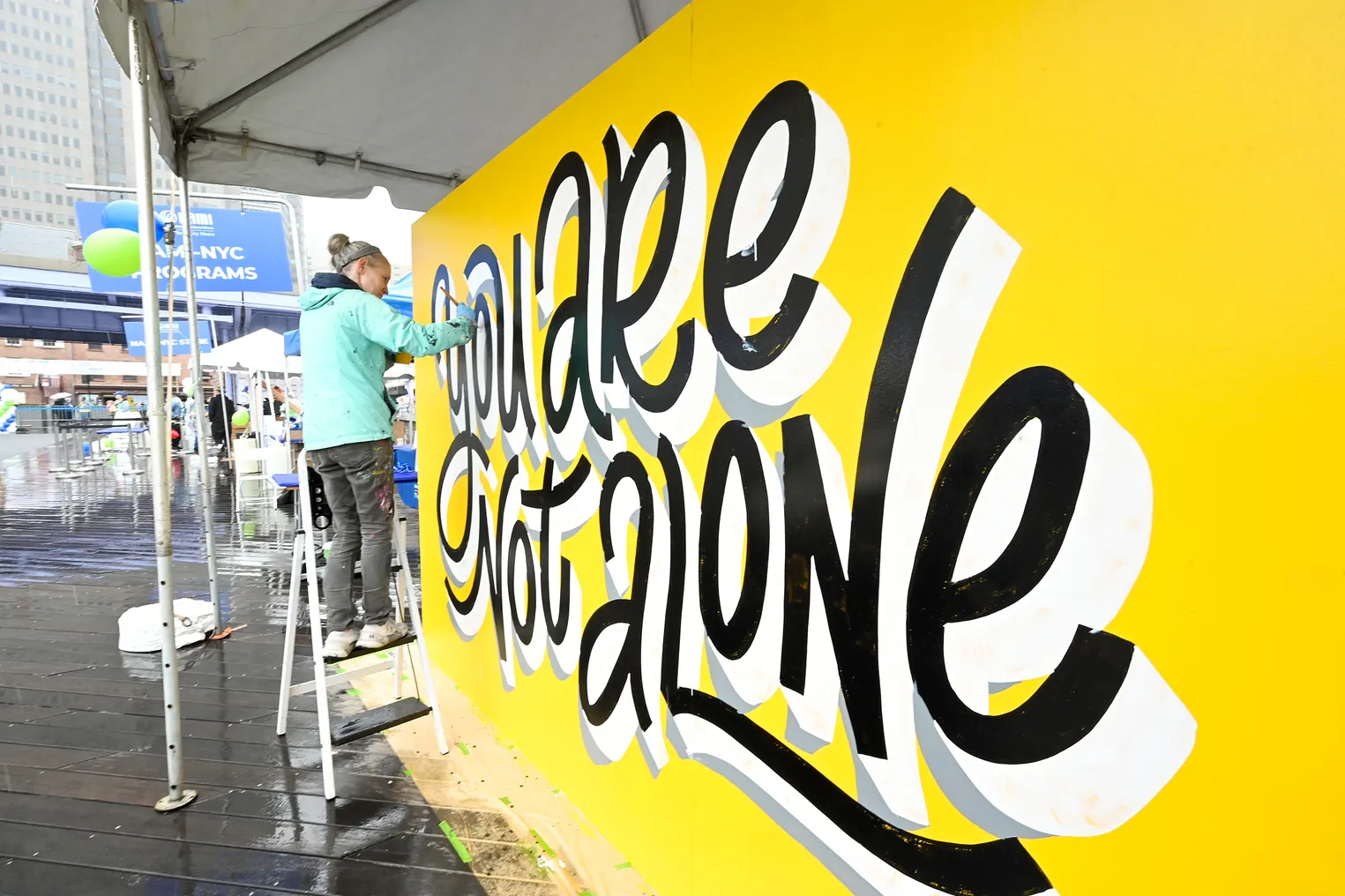 An artist paints a "You Are Not Alone" mural at a mental health awareness event in New York City.