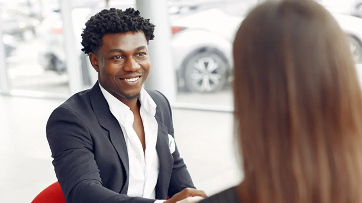 Man buying the car. Assistant helps to contract. Businessman in a car salon.