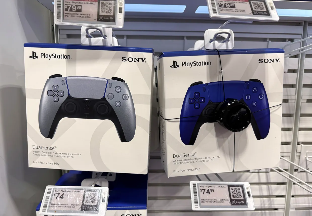 Sony PlayStation controllers displayed in packaging at a store. The packaging reads "Sony PlayStation DualSense"