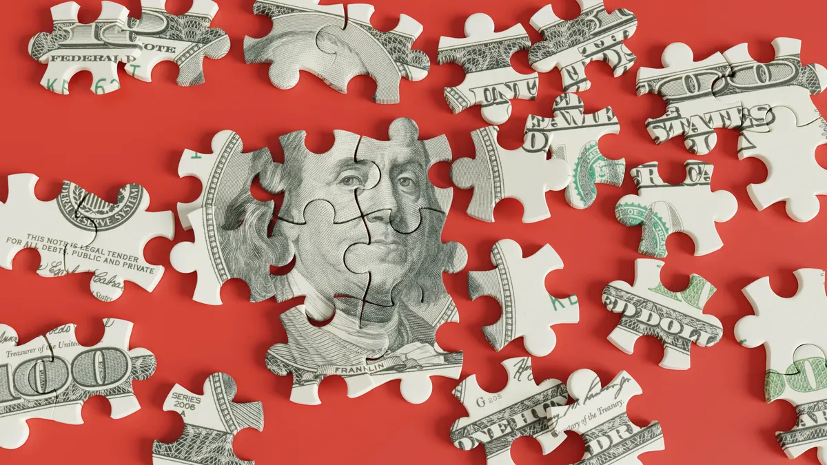 Jigsaw puzzle of US dollar 100 bill scattered on red background