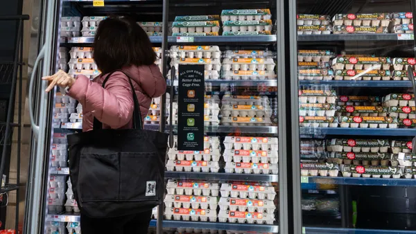 A person stands in front of a glass door containing eggs at a grocery store