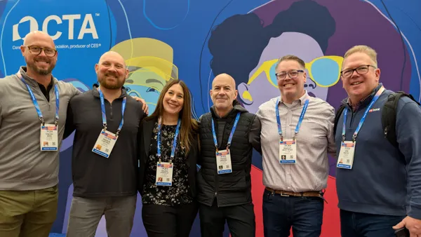 A group of six people poses for a photo in front of a colorful backdrop.