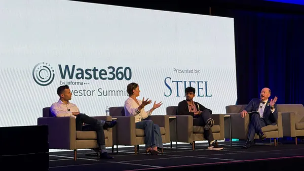 Speakers sit in chairs on a stage.