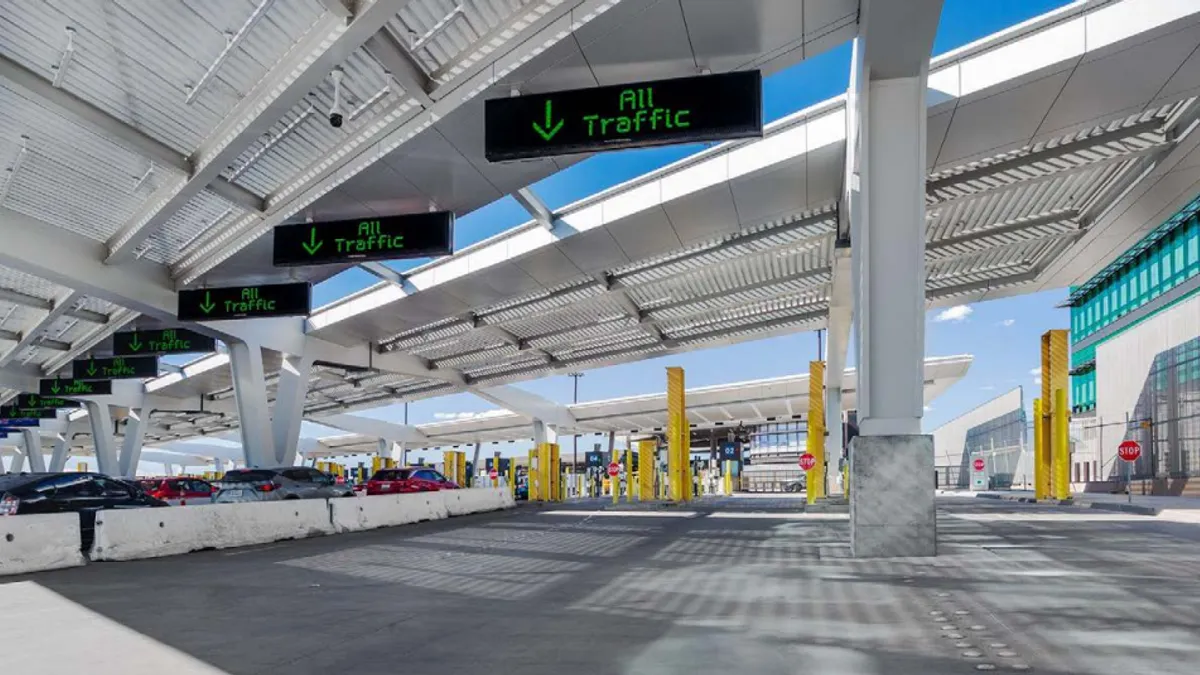 Vehicles wait under a large open canopy.