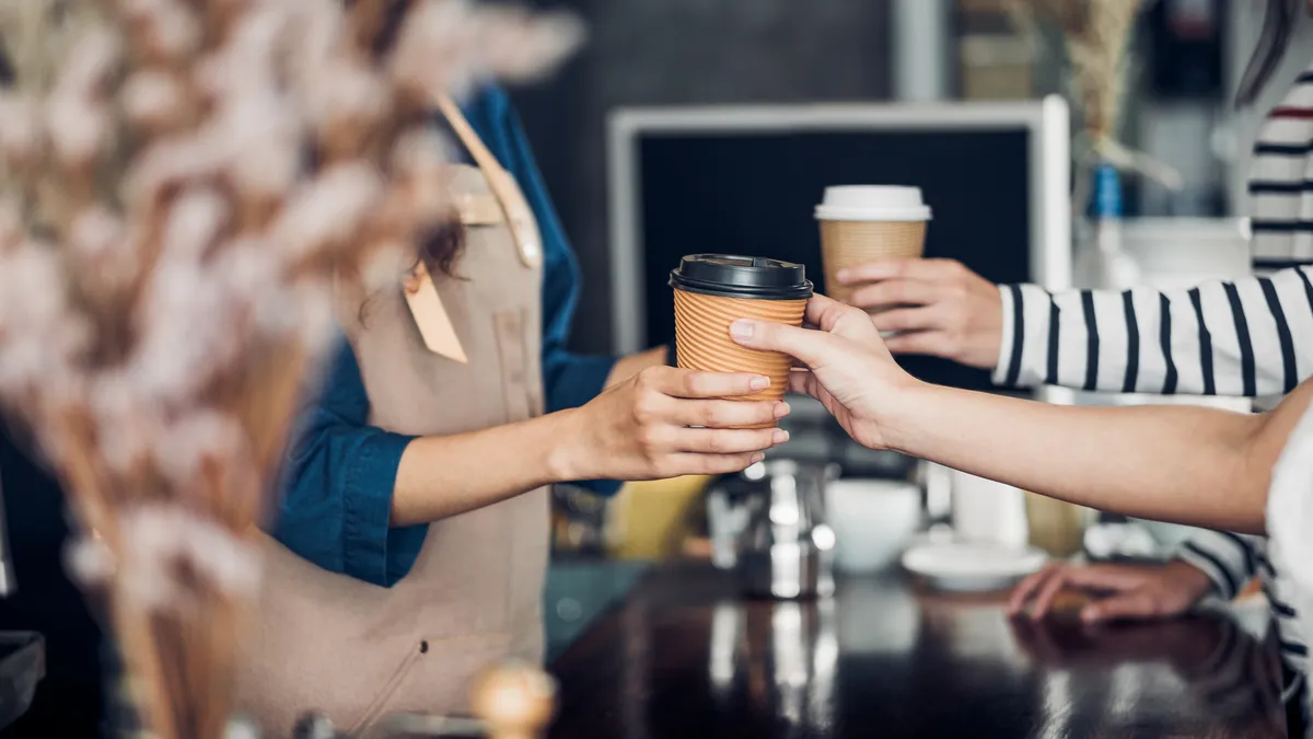 A barista hands off coffee at a cafe.