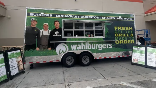 An image of a green trailer in front of a Home Depot building. The trailer says "Walhburgers" as well as "burgers, breakfast burritos, shakes ... and more"