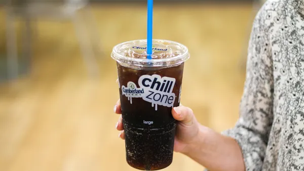A photo of a hand holding a disposable clear cup with soda inside and a straw through the lid. The cup says Cumberland Farms Chill Zone.