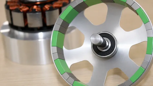 A silver and lime green circular motor, with a silver, black and copper motor device in the background.