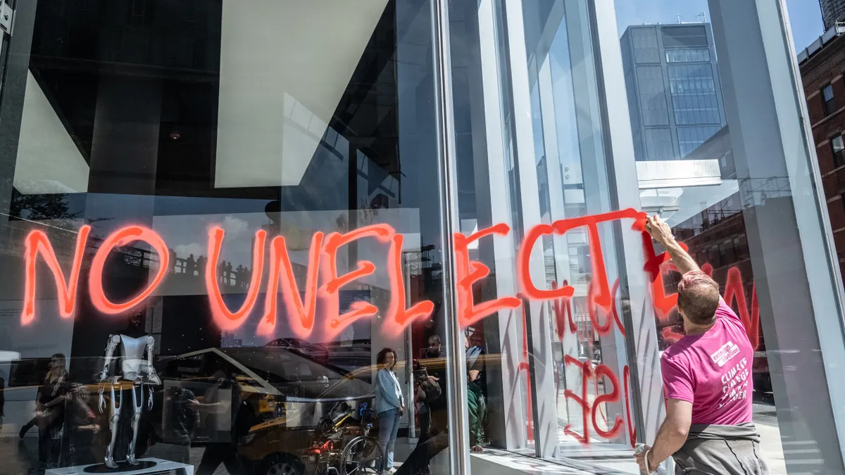 Protestors spray paint anti-DOGE messages outside an NYC Tesla showroom on Ap 22, 2025
