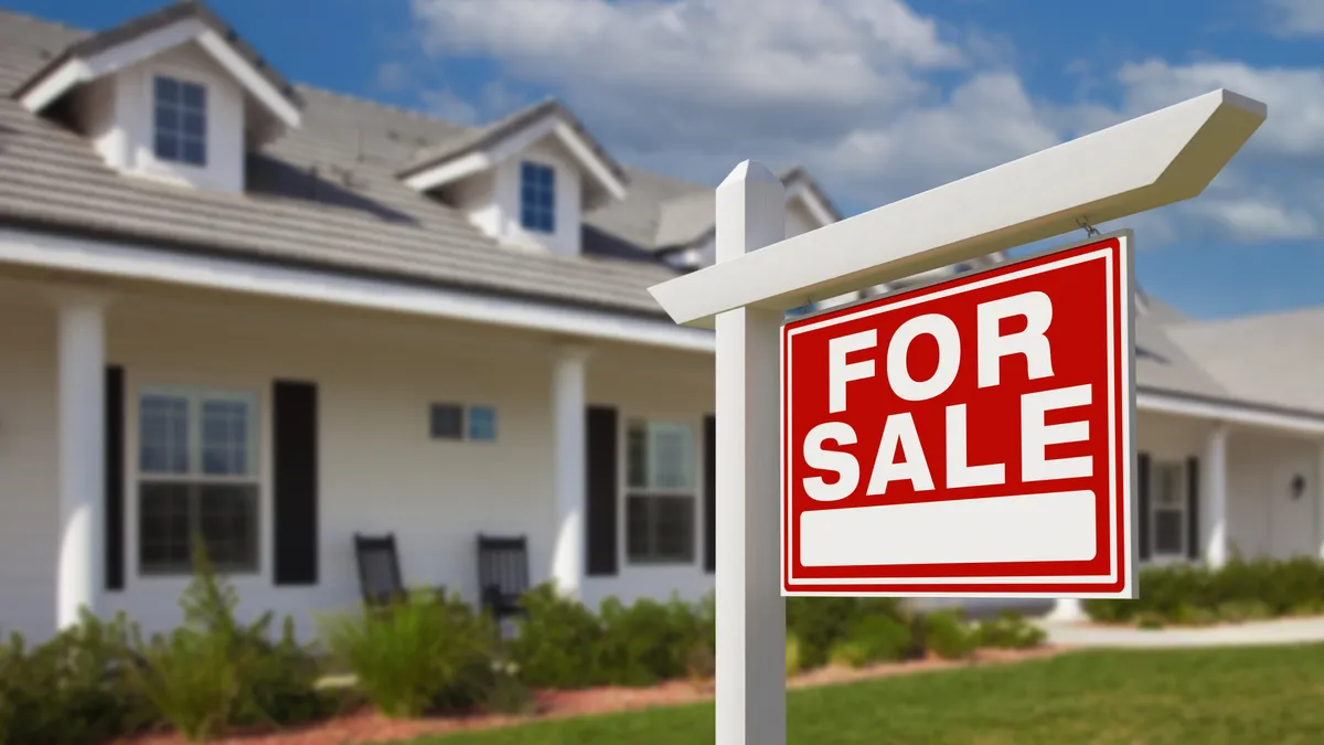 A white house with a For Sale sign in front of it.